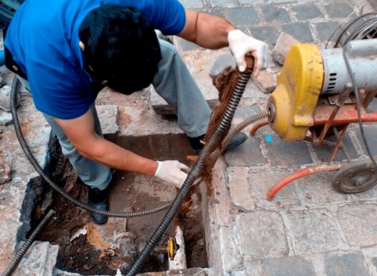 Técnico da Desentupidora BH realizando desentupimento de rede de esgoto com máquina em via pública de Belo Horizonte